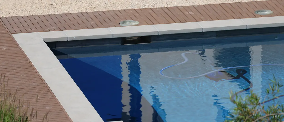 Ecke eines privaten Pools mit Skimmer und Reinigungsschlauch im Wasser